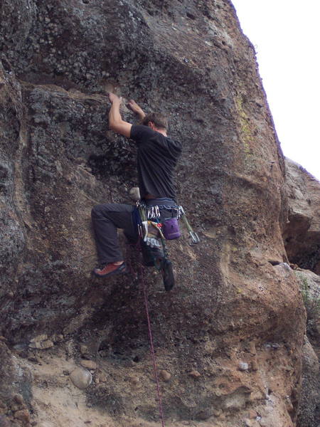 Pulling up on the descent ledge below the last bolt.