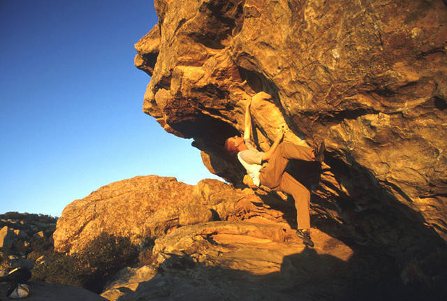 The major difficulties of "Yellow Belly" finish on the horizontal rail above the climber's left hand. Many boulderers jump or down-climb from here. Above the rail, moderate climbing on a loose flake lead to the top.