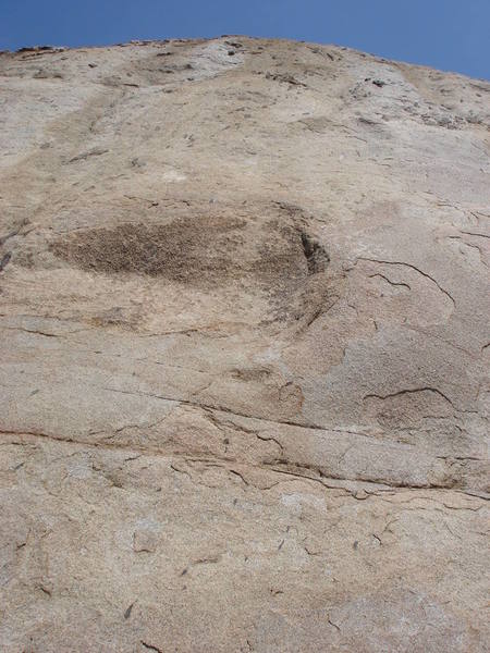 The dark brown face of Kwanku Dai. Pull straight past the bolt for the true crux. After the third bolt either head up left to the anchor atop The Hard Trough, or up right to the anchor for Headwall.