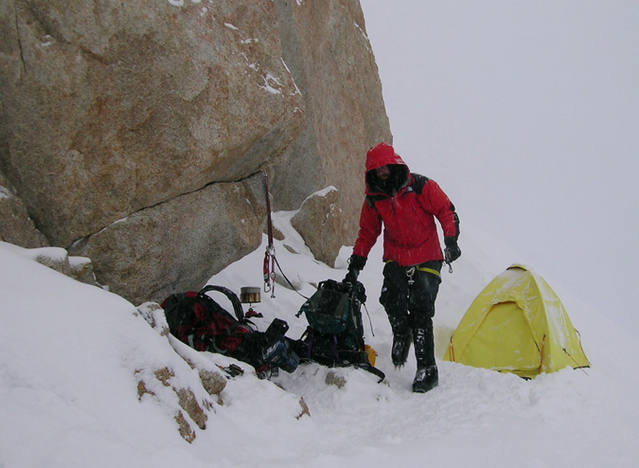 11. The camp at ~17,200' (?) above the 2nd rock band. After a few days of horrible wind and being shy on food we decided to make a run for the top. When we arrived here, we welcomed the large 'somewhat flat' area, but found it to be sloping ice, which was a lot of work to chop out. Beneath the boulder, you can find an extra rope, full sized spatula (!), and a copy of Tolkien's "Lord of the Rings"! Not sure why we didn't read it, given the bordem induced by the long storm... Photo by Avery Nelson