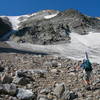 Diana Laughlin on her way to ski   Ptarmigan Glacier, although it looks like she's heading toward East Couloir. A climber can be seen as a tiny speck near the top left-hand portion of the route. This photo was taken on 7-30-2006.