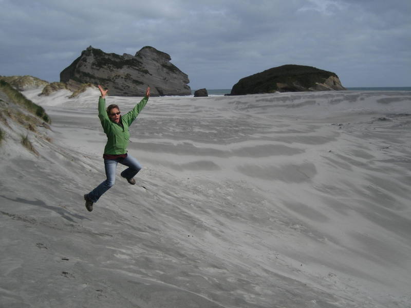 Natalie celebrates our arrival on one of the most rugged and desolate beaches we've seen yet in New Zealand, near Farewell Spit on the ocean side of Golden Bay.