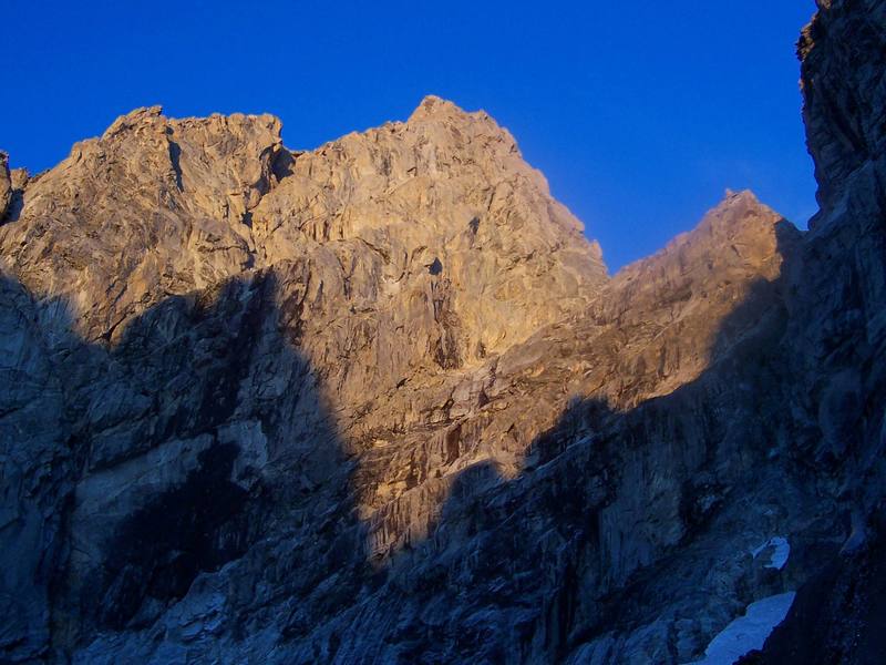 Morning sun on the Grand Teton's north side. This photo shows the East Ridge, the North Face, the North Ridge, the Grandstand, and Gunsight Notch. Taken from the Teton Glacier.