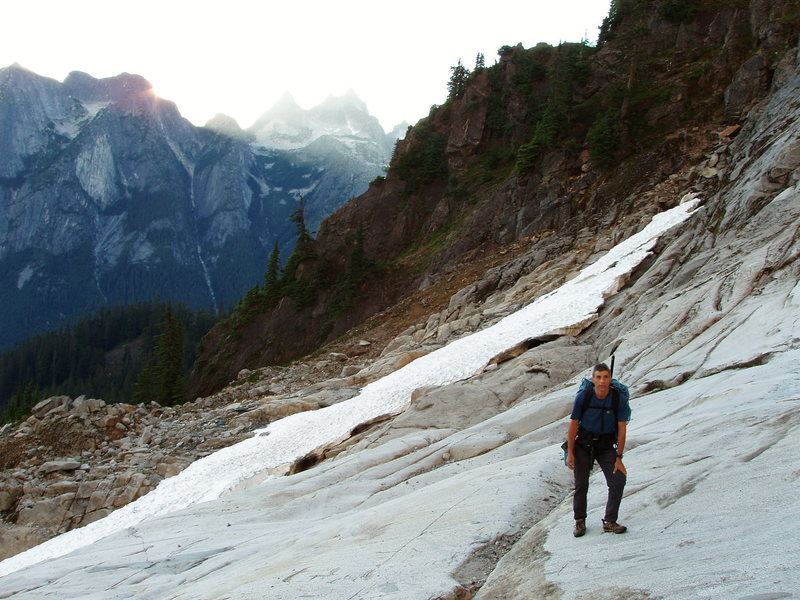 On the Bypass Glacier bedrock, with the wooded ridge between the Slesse and Bypass glaciers in the background.