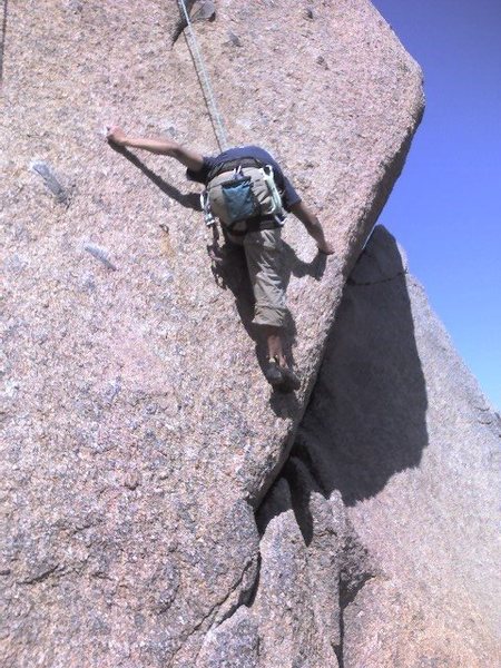 Stepping up on extremely thin holds to get to the lower portion of thin crack that trails downward to right.