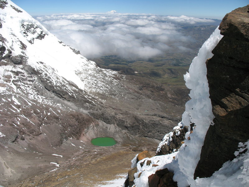 Looking down at the jade green crater lake between the Illinizas as seen from just below the summit of Illiniza Norte. Chimborazo can be seen on the horizon in the distance.