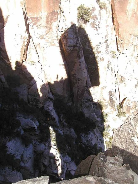 The shadow of the precariously balanced Friar pinnacle. For a sense of scale, the shadows of two climbers are visible on the ledge to the left of the huge block.