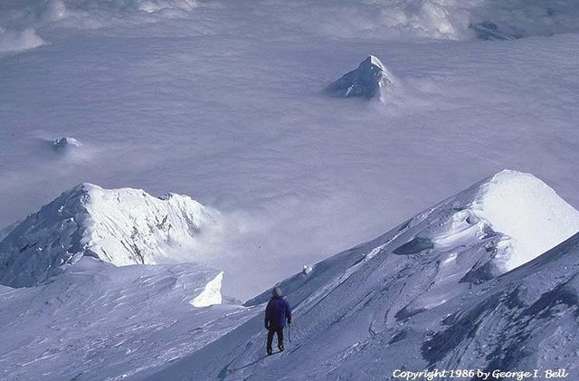Like a shark fin, the summit of Mt. Huntington pokes out of the clouds in this view from 19,000' on the South Buttress of Denali.