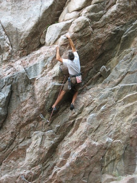 Dan Miller grapples with the slopey rounded holds at the crux of the 1st pitch of Spider Pig 5.11a.