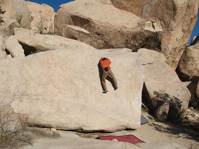 Past the crux and ready to mantle over on Lip-Synch (V1), Joshua Tree NP