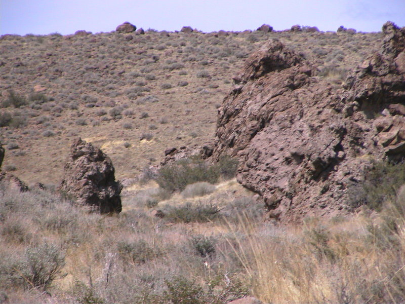 The river bed boulders as seen from the parking area. The rough roof is the small boulder closest to us and the warm up boulder is the massive boulder in the back ground. The boulder on the left has a few V-easy problems but nothing worth doing.