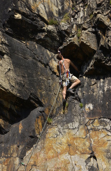 Sunday Morning Crack is below the climber. When he passes the roof, he will use the undercling to step left to the arete, then climb to the headwall, and finish in the vertical black crack near the top of the south face.