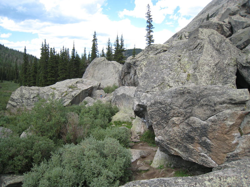The Ladder Boulder is the large, flat-topped boulder on the left. The Ladder climbs the shaded face in front of the climber.<br>
<br>
The two hanging aretes in the forground are Ben's Arete (the nearest arete) and Maker's Mark (the darker arete).<br>
<br>
The towering boulder behind the climber is the Bierstadt boulder. Timeline & Canvas climb the face shown here.