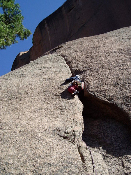 You can squeeze through (maybe) from the inside to this position, or you can climb the outside and then swing into the squeeze. From here, it's a struggle to reach the jams at the base of the crack.<br>
<br>
Photo by Paul Rezucha.