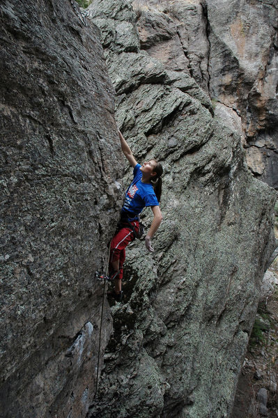 Searching for holds on the thin arete that guards the anchors.