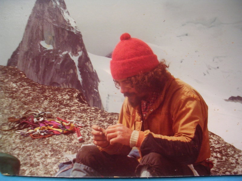 Alain Henault, 1974, rolling up a quick smoke on the summit of Snowpatch Spire. He and his wife had been zapped the day before on North Howser and we only stayed a few minutes. <br>
<br>
I should have smoked a cig too. The first rap anchor was an easily portable flake laid across the top of the crux chimney on Kraus-McCarthy.<br>
<br>
The rack in back was completely nuts too!