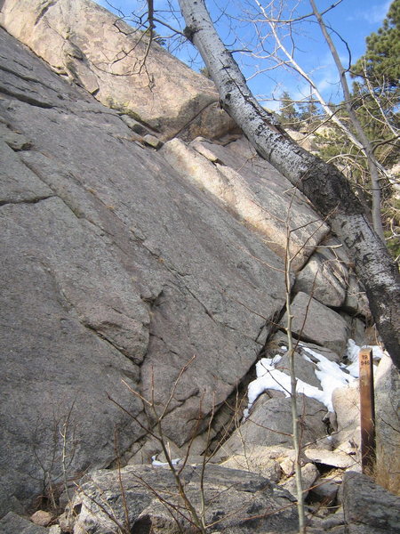 Le Petit Francais climbs the sunlit, left-facing dihedral just behind the trail marker in this photo.