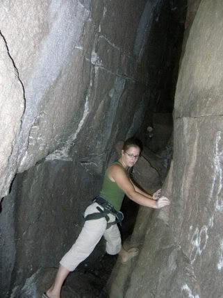 Meg at the start of the "Devils Den" cave. From here the fissure goes back horizontally for 30-40 feet, then escape is made by ascending a 14' +/- ladder. One can also exit by continuing left at the ladder, chimneying up towards daylight, and then popping out of a smallish hole atop a sizable drop off.<br>
<br>
Headlamp or flashlight recommended for your first time exploring the cave.