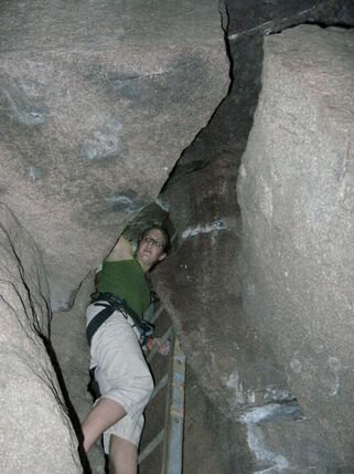 Meaghan ascends the ladder to escape the Devils Den cave. The ladder, maybe 14 feet tall, is wedged in a tight confine and most people climb it with their back on the opposite wall to stabilize the "wobble." Above the ladder, a couple easy scrambling moves lead to the top.