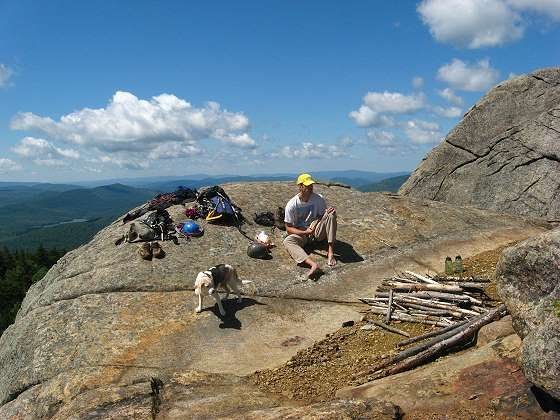 Jason relaxes along with wundermutt Aslan on the Second Prow. The route <em>Rock of Ages</em> tops out on the First Prow behind him.