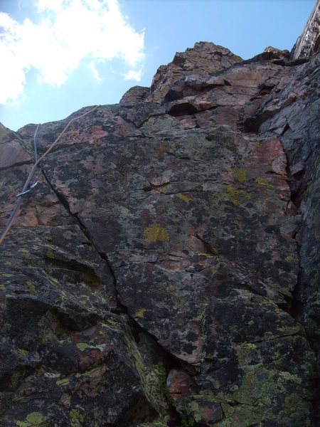 At the bottom of the first pitch. The end of the pitch is up and slightly over the pinnacle at top.