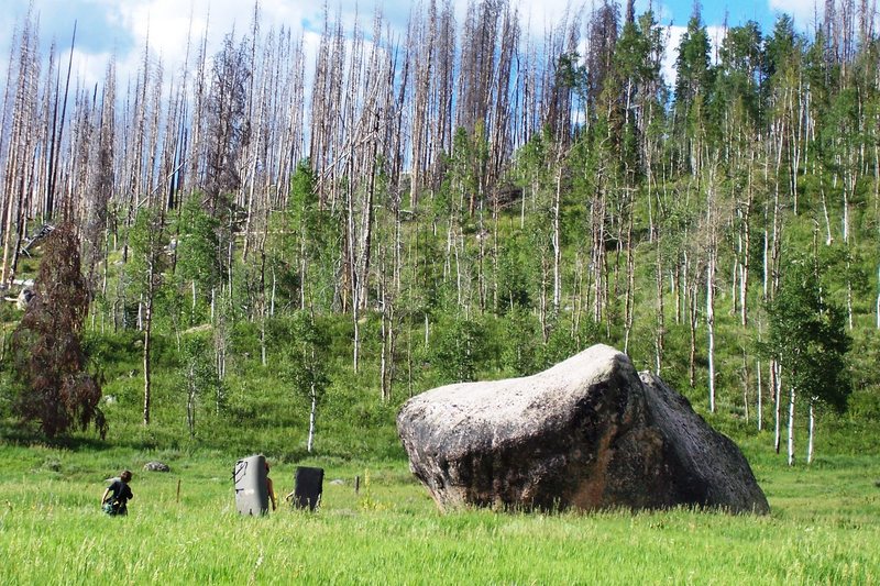 Walk across the field to approach the boulder. The first problems encountered are located on the most overhanging side of the boulder.