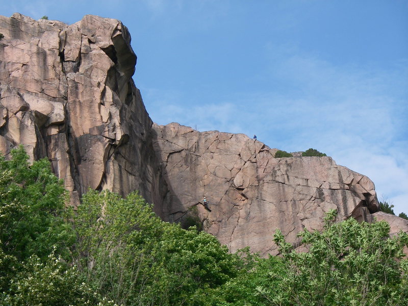 The Mallorol Wall. The route "Mallorol" follows the crack system up to the obvious left facing flake, then up and right to the top of the wall (belayer visible at the top of the route).<br>
<br>
The climber in turquoise on the route to the left is on "Chapman", which shares a start with "Mallorol".