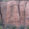 "K-9" ascends the narrow, left-leaning orange buttress on the left side of the photo, below and left of the climber in white. The climber is on "Welcome to Echo Cliffs."