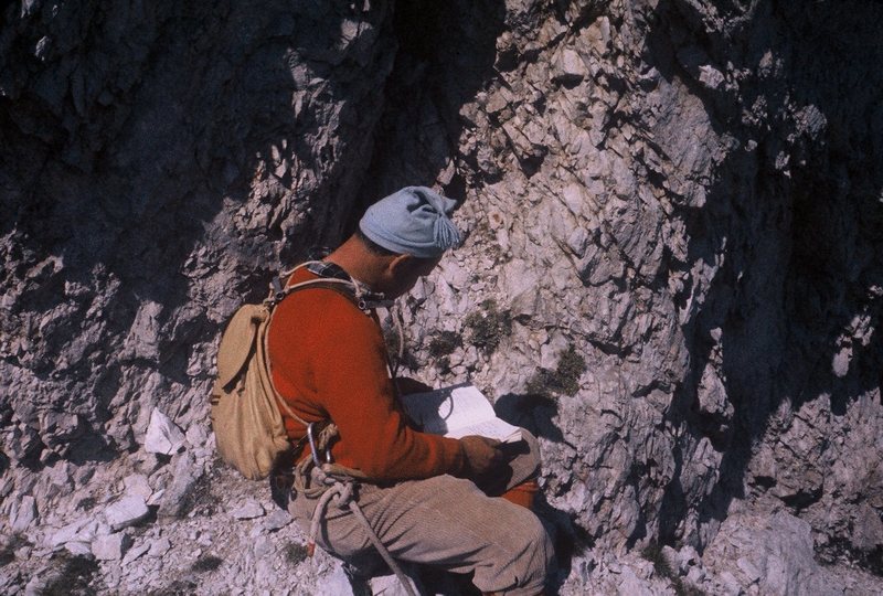 "Toto" signing the route register, which is on a ledge one pitch below the summit.