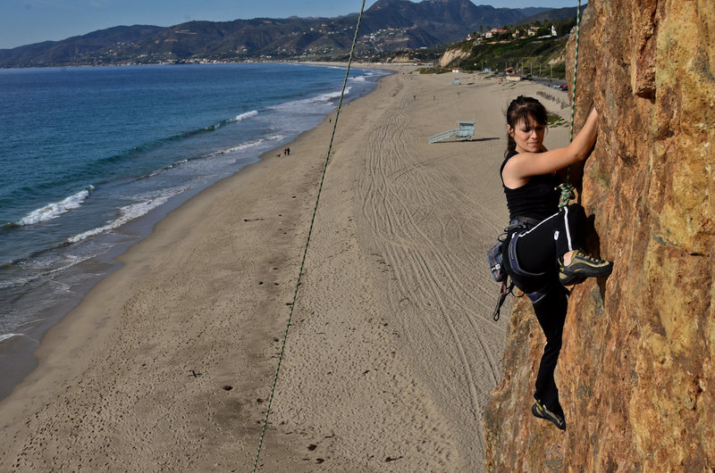 Sara climbs a route on the seaside on a beautiful day.