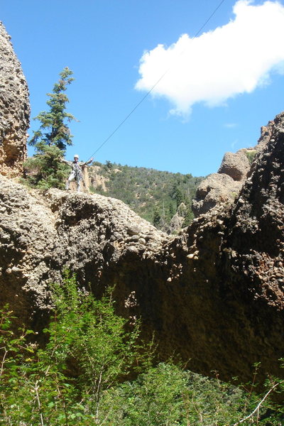 George Bracksieck standing on the higher (west) end of the Natural Arch, Aug 29, 2011. Despite visual competition from the sunlit tree canopies, the dark span of the arch and its lower edge are visible near the bottom of this photo. I found no cairn or other evidence of previous human visitation anywhere atop the arch. I left no trace of my visit.