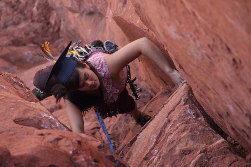 Sarah climbing pitch one in graduation garb