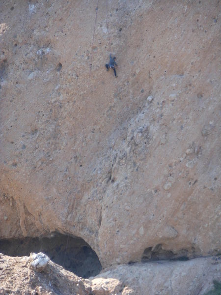 A climber working the moves on a 5.10 route that ascends the left side of the isthmus.