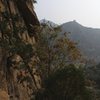A climber just to the right of "Balance." The route starts on the big, flat face (more obvious when standing underneath it). to the climber's right. <br>
<br>
If you look closely in the distance, you can also see one of the older sections of the Great Wall of China!
