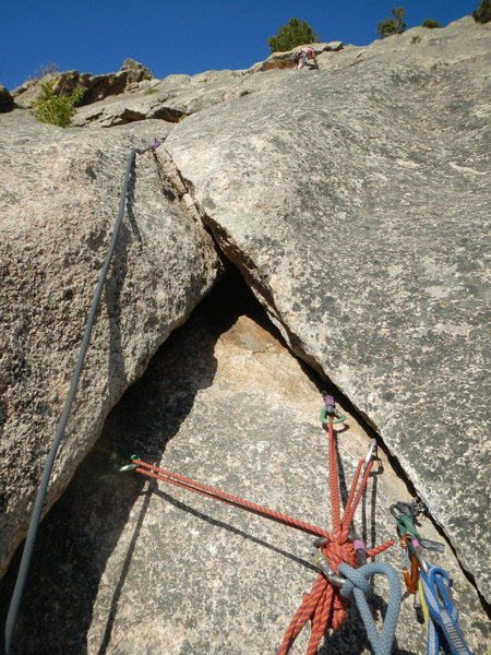 Belay anchor at the top of P2, with Kate heading up P3 to the tree belay, walk-off ledge.