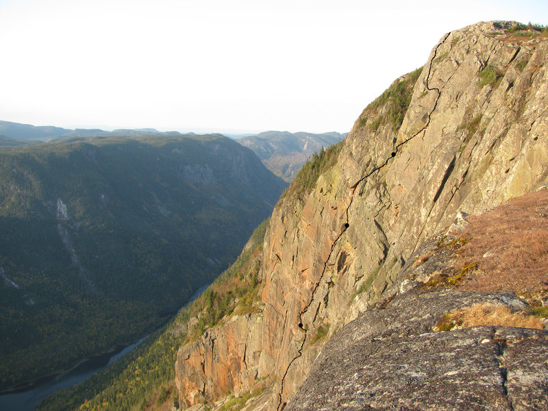 The last pitch is a traverse on the big flake at the right to the bushes diedral.<br>
<br>
La dernière longueur: Quitter le dièdre végétal vers la droite pour monter sur un gros feuillet aérien, aller jusqu'au bout...