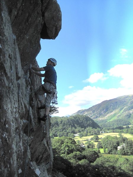 P.Ross near end of traverse P2. The Direct Finish climbs over the roof to his left.