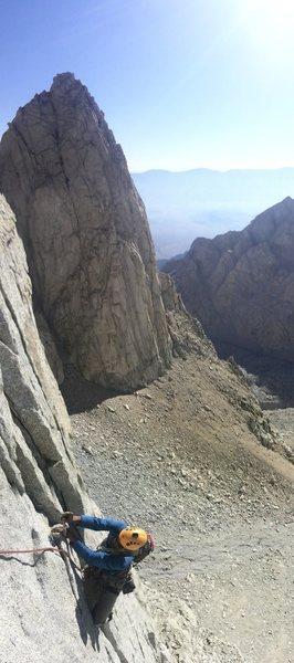 Climbing on Pitch 4 of the route with the attractive Shaw Spire in the background.