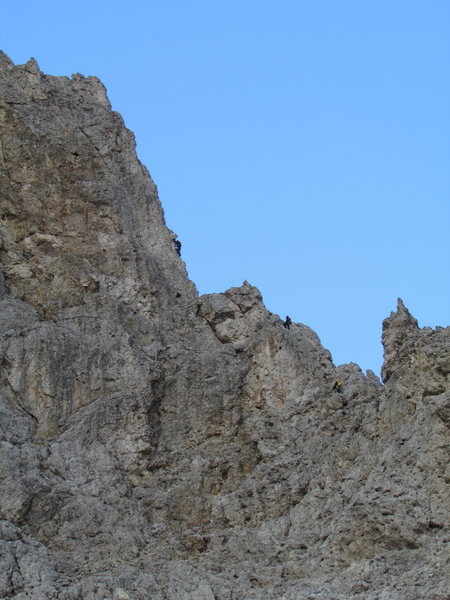 Climbers silhouetted on the steepening arête.