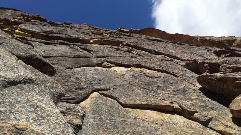 View from the ground. The first pitch goes up the flake on the right past two bolts and aims for the left side of the large roop at the top of the photo.