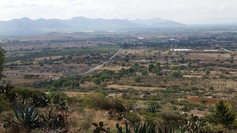 Looking roughly west toward Mexico 130 from the Las Bolas cliff. The obvious paved road is used for access to the crag. The weird housing area mentioned in the approach description can be seen in the left foreground.