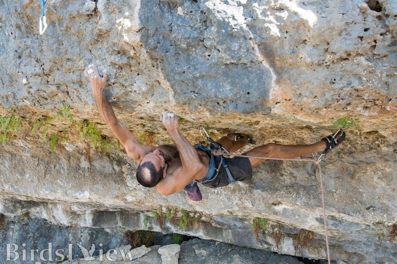 Rupesh sticking the first hold above the lip, prepping to toss for the next hold above. The crux