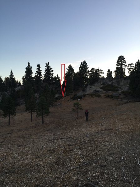 about 1 mile into the hike and passing several Climbing Post signs, you will hit a logging road then his open field. Head towards the hills to a log on the ground with a large Cairin as seen by the red Arrow