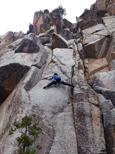Mark Jenkins doing the crux slab traverse on Hippophobia (5.10). The route continues up the left crack, moves left to another crack, then steps back right below the upper roof, taking the easiest line through the main roof/prow. Belay/rappel tree visible at the top.