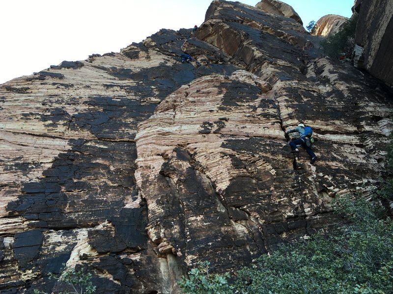 Three climbers simulclimbing pitch 3, outlines the route, starting from crack near right end of terrace, in the route description.