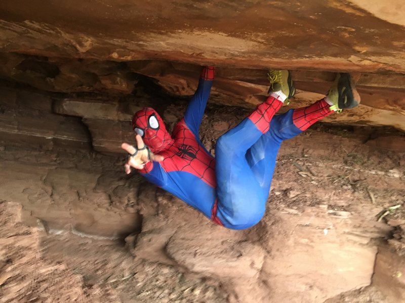 spider man holding rock above ground
