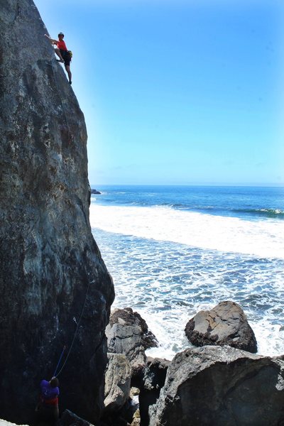 Nick closing in on the anchors as waves crash beneath him. True West Coast climb.