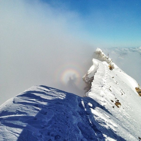A sick and rare phenomenon called brocken spectre, where a magnified shadow appears in the clouds opposite the sun. Lucky here to have it on the summit of the Matterhorn.