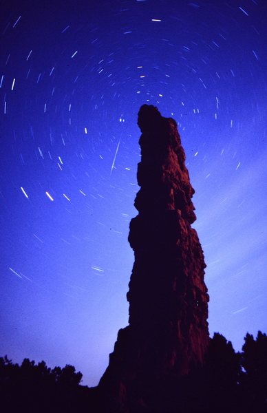 This is the Standing Rock of the Maze, aka Candlestick Spire, at night with a meteor behind.
