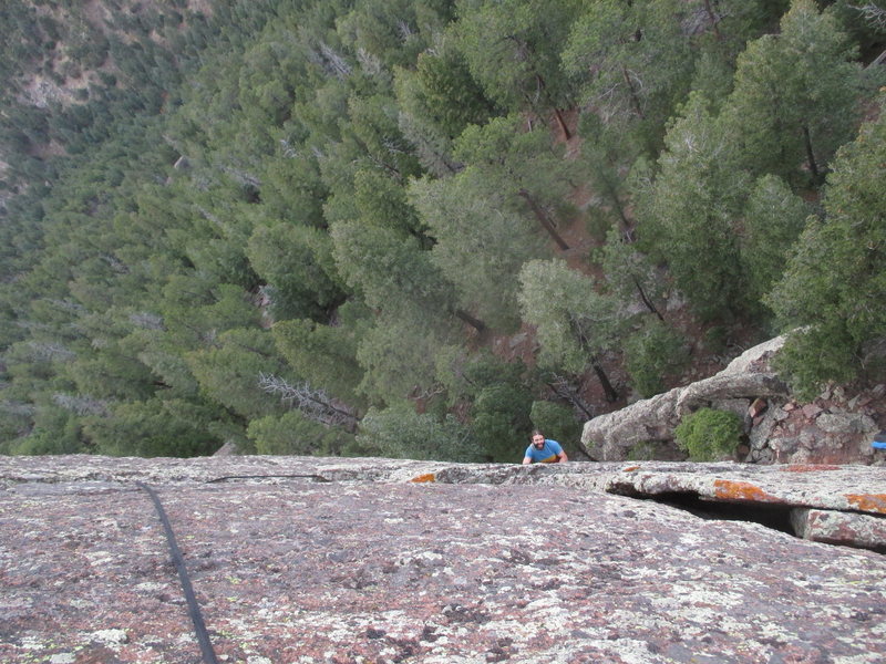 Kendrick C. appears, having emerged from below the roof crux on 'North Crack' (5.10) on the Main Crag at Sacred Cliffs.